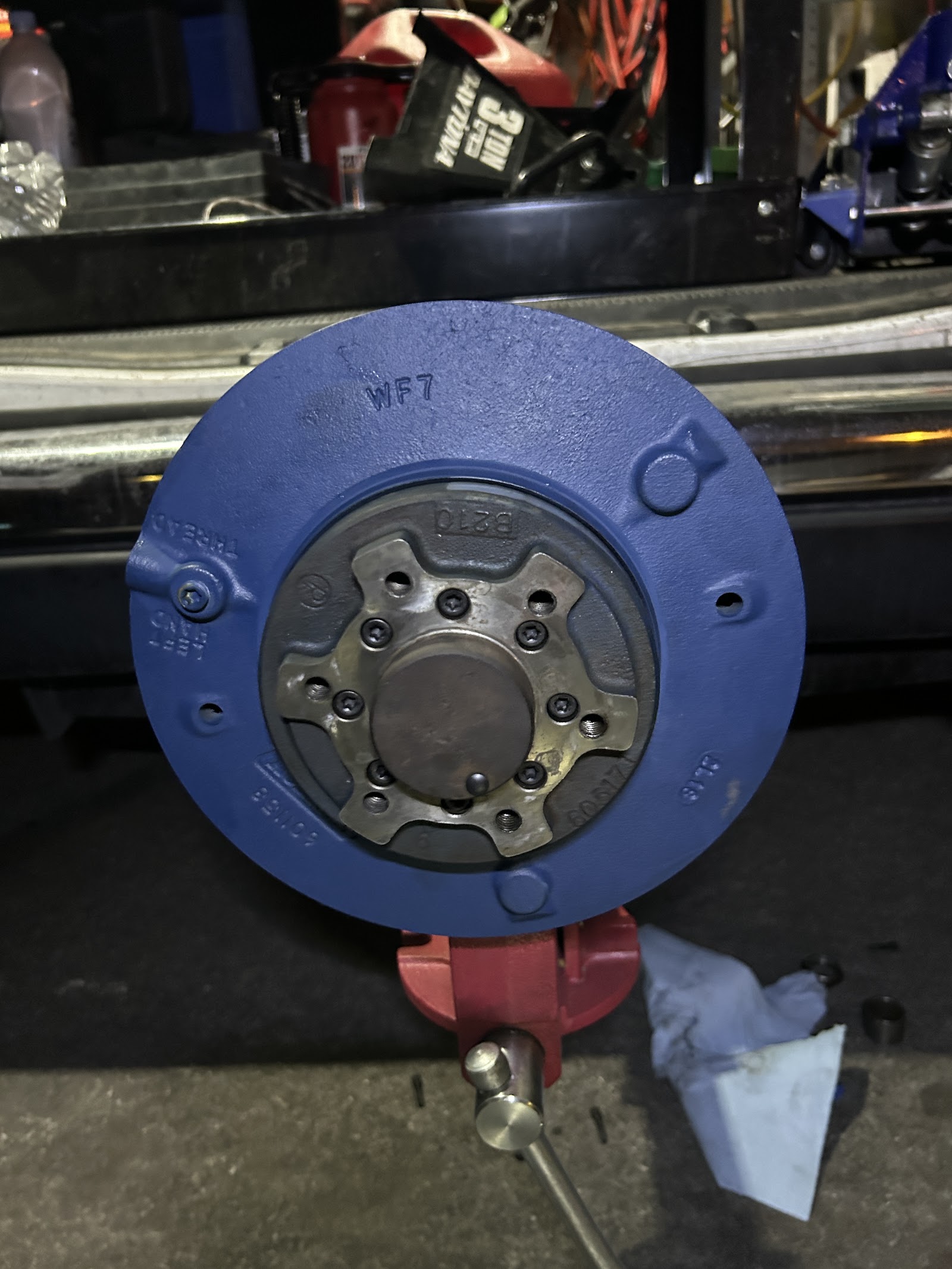 Freshly painted blue brake drum and hub assembly mounted in a bench vise