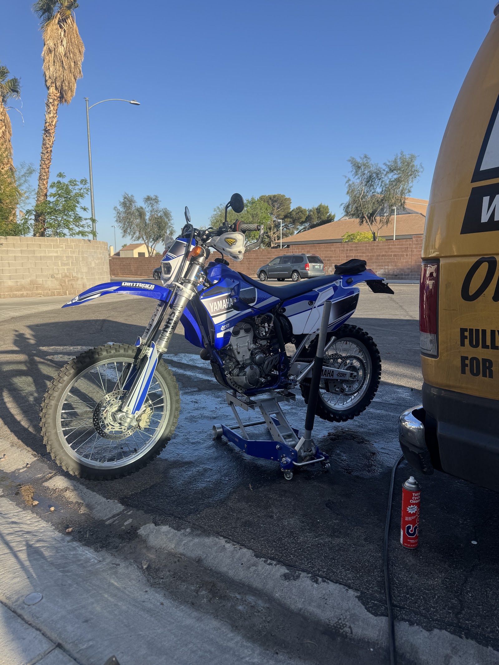 Blue Yamaha dirt bike on a lift stand being serviced next to the service van